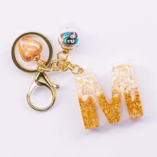 STORELUXY Pearl and Glittery Gold Evil Eye Initial Keychain With Good Luck Amulet Protection Charm and Heart Pendant Suspended in High Quality Resin Personalised In Letter M